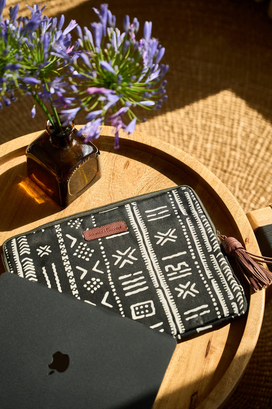 Black and white patterned laptop sleeve with a leather tassel and tag.