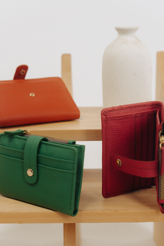 Three compact bifold wallets in Saffiano Orange, Ultra Marine, and Radiant Orchid colors, Zipper and Button detail