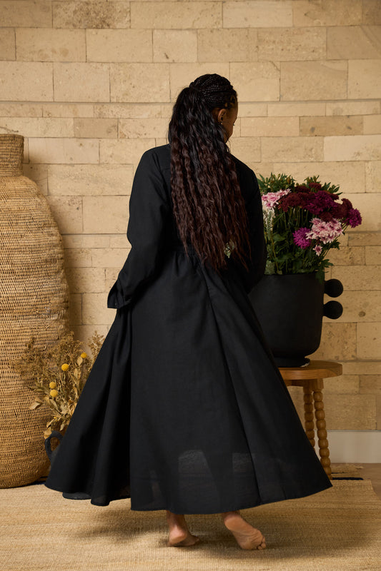A black midi skirt made of linen blend, designed with pockets, pleats, and an elastic waistband for comfort.