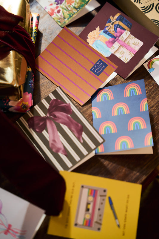 Flat lay of colorful assorted stationery cards and wrapped gifts, including striped and floral greeting card designs.