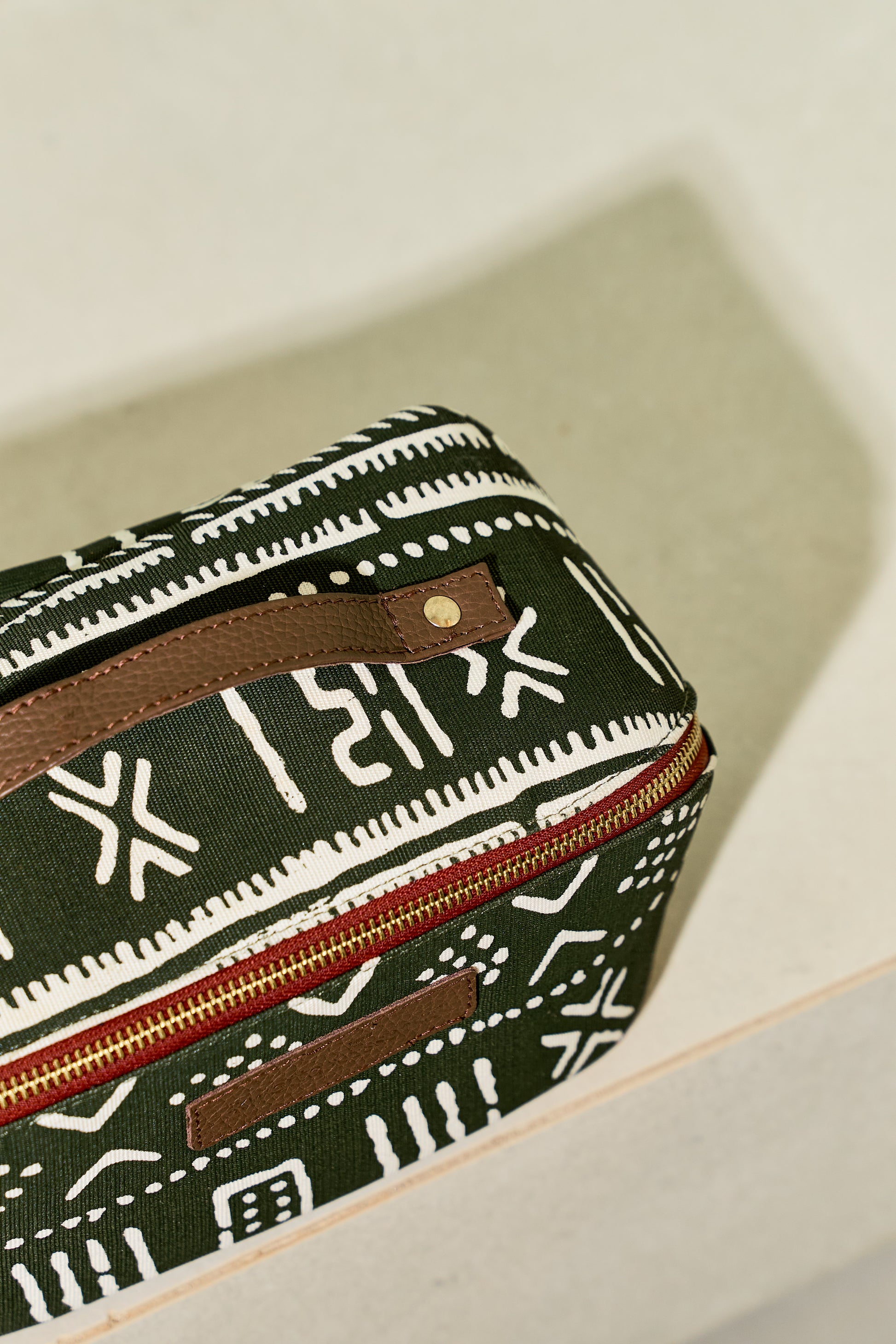 Zola toiletry bag in green/white print, top view.