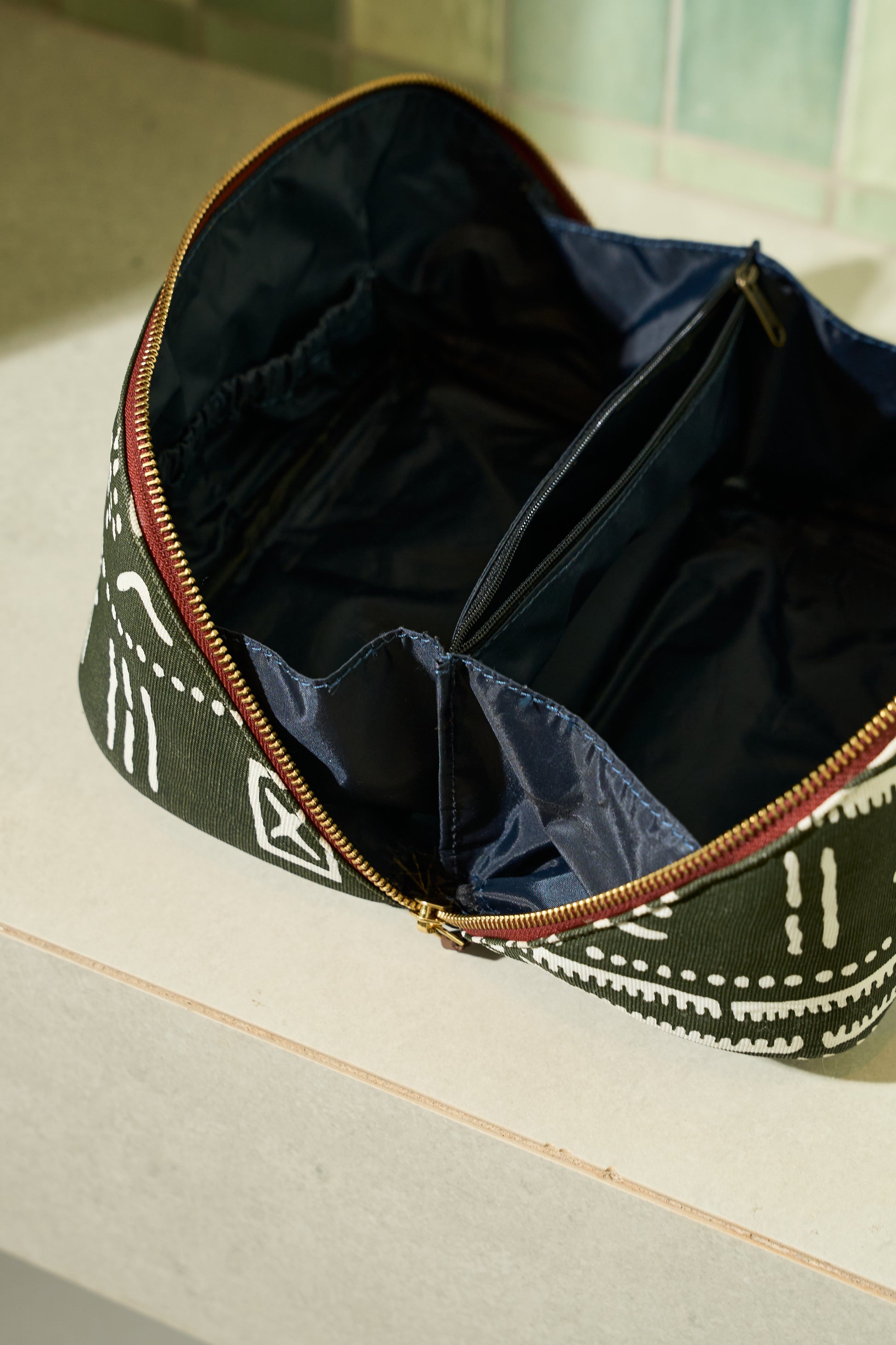 Zola toiletry bag showing two spacious compartments, four interior pocket sleeves, and Navy waterproof lining.